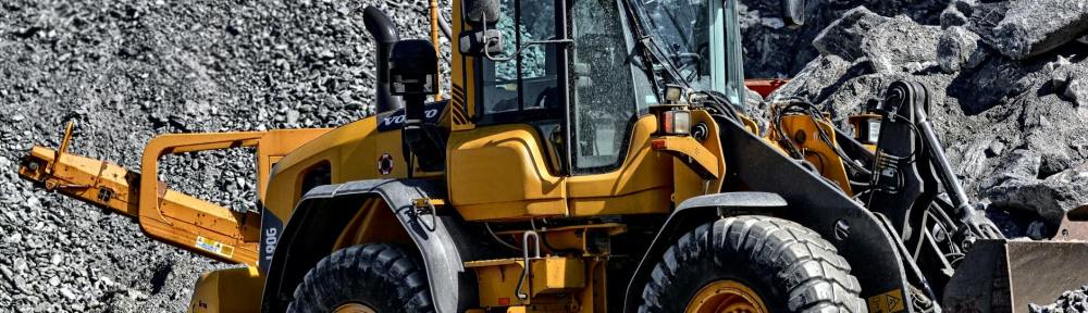 orange and black tractor next to piles of rocks